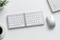 Wireless mouse and foldable keyboard bundle flat lay on minimal desk surface